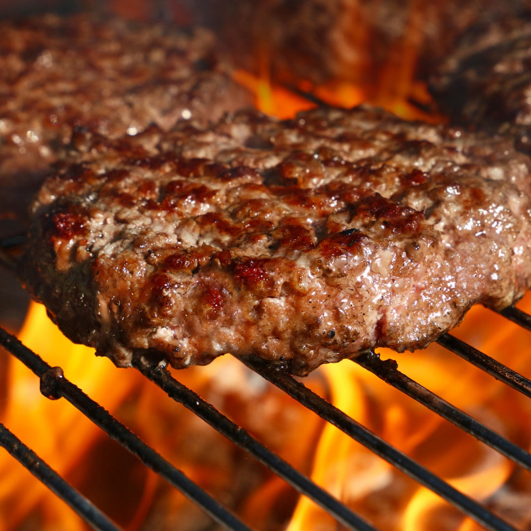 SIZZLING BURGERS ON GRILL WITH RED HOT FLAME